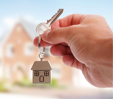 Mão segurando a chave de um imóvel com chaveiro em formato de casa